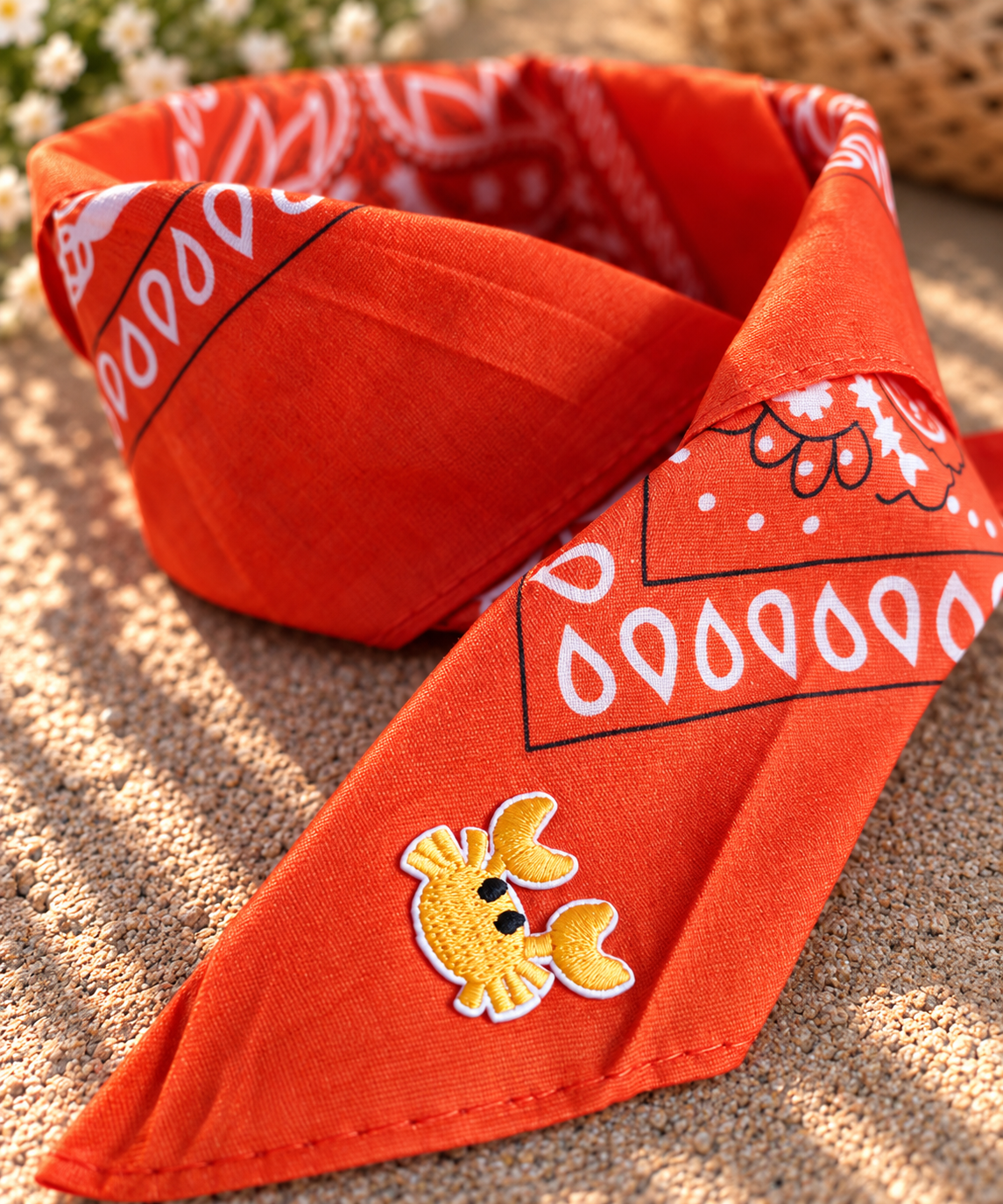 Close-up van het embleem van een geel krabbetje op de Crabby Orange kinderbandana