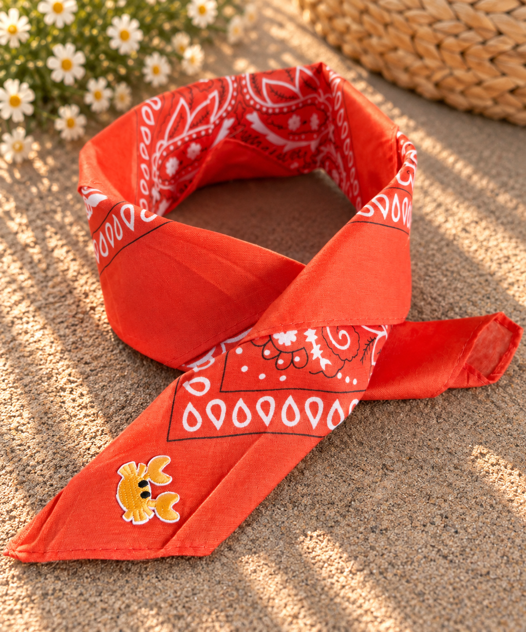 Crabby Orange kinderbandana in oranje paisley, opgevouwen met een embleem van een geel krabbetje op de punt
