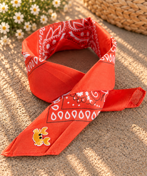 Crabby Orange kinderbandana in oranje paisley, opgevouwen met een embleem van een geel krabbetje op de punt