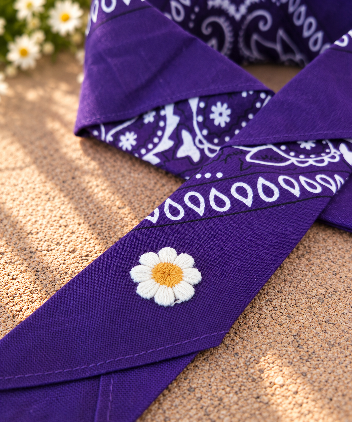 Close-up van het embleem van een wit madeliefje op de Daisy Purple kinderbandana