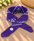 Daisy Purple kinderbandana in paarse paisley, opgevouwen met een embleem van een wit madeliefje op de punt