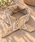 Desert Honey Bee kinderbandana in zandkleurige paisley, opgevouwen met een embleem van een bijtje op de punt