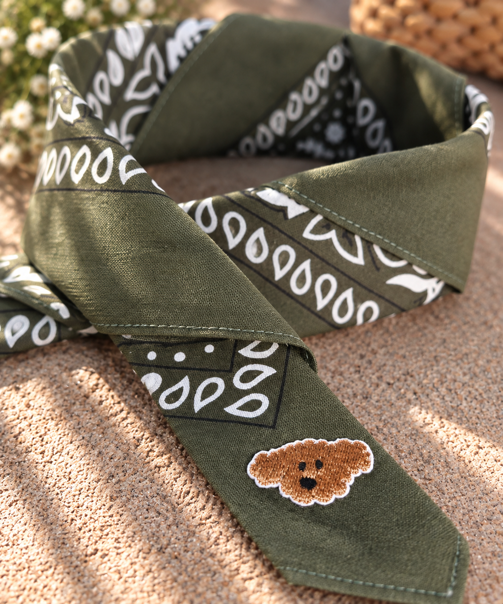 Close-up van het embleem van een bruin hondje op de opgevouwen Doggy Green kinderbandana