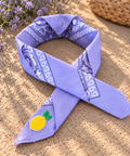 Lemon Lilac kinderbandana in lila paisley, opgevouwen met een embleem van een gele citroen op de punt