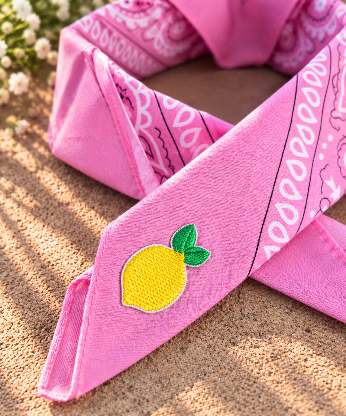 Close-up van het embleem van een gele citroen op de Lemon Pink kinderbandana