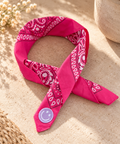 Smiley Fuchsia kinderbandana in fuchsia paisley, opgevouwen met een embleem van een lila smiley op de punt