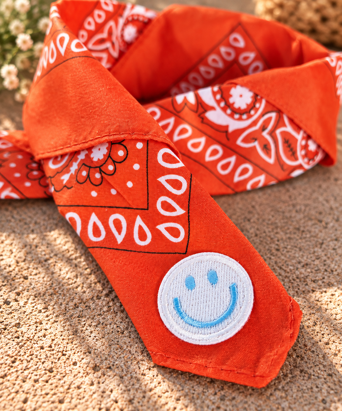 Close-up van het embleem van een lichtblauwe smiley op de Smiley Orange kinderbandana