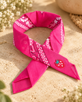 Strawberry Fuchsia kinderbandana in fuchsia paisley, opgevouwen met een embleem van een rode aardbei op de punt