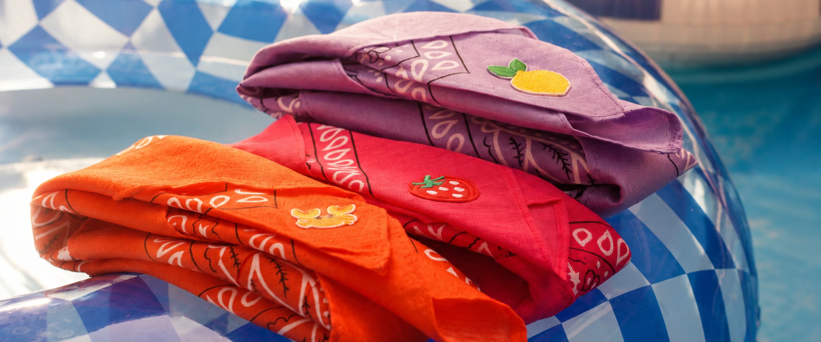 Kleurrijke Tiny Ties bandana’s op een blauw zwembandje in de zon